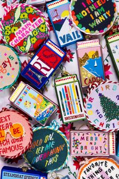 many different types of embroidered badges and magnets on a white tablecloth with words written all over them