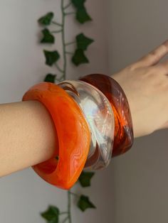 Make a bold, retro statement with this unique set of three chunky resin bangles! Featuring vibrant shades of orange, brown, and clear resin, these eye-catching accessories are perfect for adding a pop of colour and vintage flair to any outfit. ✨ Features 1) 3 Distinct Bangles:   - Includes three resin bangles in shades of bright orange, brown and clear resin. Each bangle has its own distinctive charm, making this set versatile and fun to mix and match. 2) Chunky, Bold Design:   - These bangles f Chunky Colourful Jewelry, Orange Bangle With Colorful Beads, Bohemian Orange Bangle Jewelry, Vintage Resin Bracelet, Jewellery Minimalist, Vintage Resin Bangle, Vintage Lucite Bangle Bracelet, Minimalist Jewellery, Resin Bangles