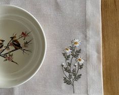 two birds sitting on top of a white plate next to a small flower and plant