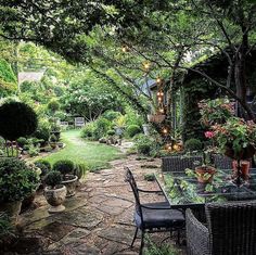 an outdoor dining area in the middle of a garden with lots of plants and flowers