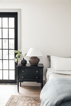 a bed room with a neatly made bed and a night stand next to a sliding glass door