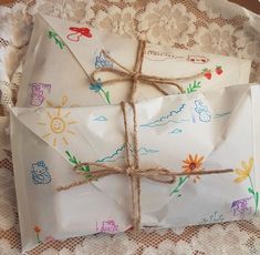 an envelope wrapped in paper and tied with twine on a lace doily covered tablecloth