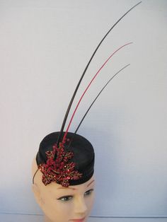 "* Designed on a black Sinamay pillbox hat form this hatinator will take you anywhere you want to go and will catch many eyes. The design includes a wide black leather braided trim complemented by handmade red sequen and bead worked Maple Leaves. To add a touch more of detail shiny red berries look good enough to eat. * The three black and red quills give dramatic height to the piece and upon ordering this is the exact fascinator you will receive. * With a hat diameter of 5.5\" it qualifies as f Black High Crown Fascinator With Adjustable Fit, Black Mini Hat With Pinched Crown For Formal Occasions, Black Formal Mini Hat With Pinched Crown, Black Mini Hat With Pinched Crown For Evening, Black Adjustable Fascinator With Structured Crown, Black Costume Hat With Pinched Crown And Adjustable Fit, Black Adjustable Mini Hats With Pinched Crown, Adjustable Black Costume Hat With Pinched Crown, Black Costume Hat With Adjustable Structured Crown