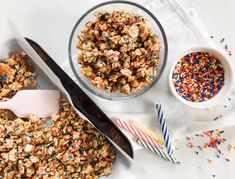 sprinkles and cereal in bowls on a white tablecloth next to a pair of scissors