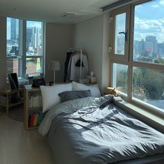 a bedroom with large windows and a view of the city from it's bed