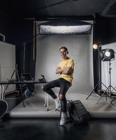 a man sitting on top of a suitcase in front of a camera and lighting equipment