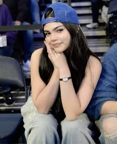 a woman sitting in the stands with her hand on her chin and looking at the camera