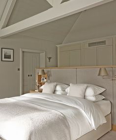 a bed with white sheets and pillows in a bedroom