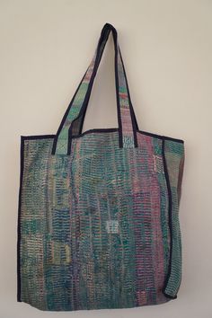 a multicolored tote bag hanging on a wall next to a white wall