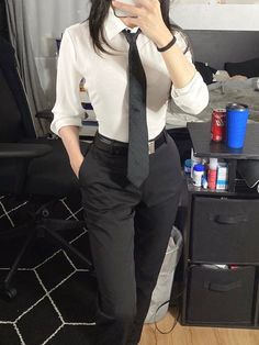 a woman in a white shirt and black tie taking a selfie with her cell phone