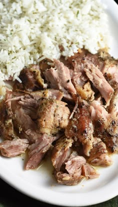 a white plate topped with meat and rice on top of a green table cloth next to a fork