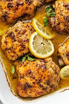 chicken thighs with lemons and herbs in a white casserole dish, ready to be eaten