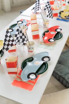 a long table topped with plates and cups filled with race car themed desserts on top of each other