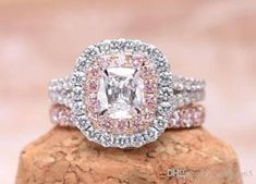 an engagement ring on top of a rock with pink and white diamonds in the center