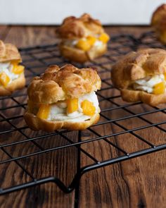 several small pastries on a wire rack with some fruit in the middle and one is filled with cream cheese