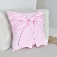 a pink bow pillow sitting on top of a white couch