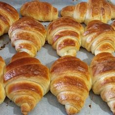 many croissants are lined up on a baking sheet and ready to be baked