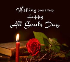 a red rose sitting on top of a table next to a candle and book with the words wishing you a very happy all soul's day