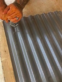 a man holding his hand on top of a metal sheet