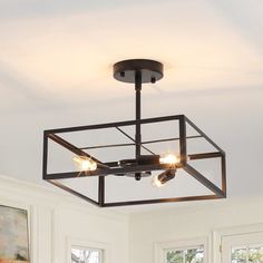 the light fixture is hanging from the ceiling in the room with white walls and windows