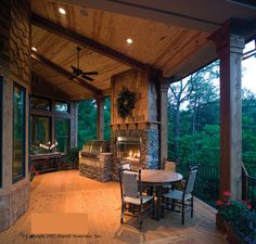 a covered patio with table and chairs next to an outdoor fireplace in the middle of it