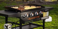 an outdoor grill with food cooking on it's side in the middle of grass