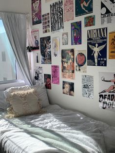 a white bed sitting next to a window covered in posters