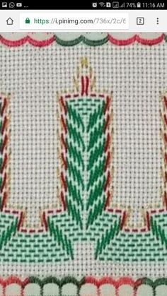 a close up of a cross stitch pattern on a piece of cloth with candles in the center