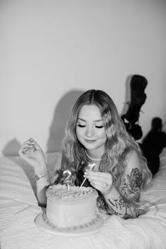 a woman sitting on top of a bed with a cake