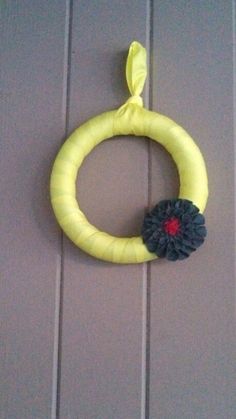 a yellow wreath with a black flower hanging on the front door to show it's age