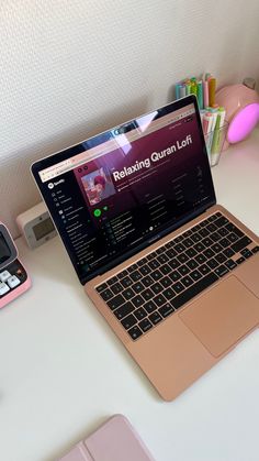 an open laptop computer sitting on top of a white desk next to a pink phone