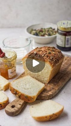 a loaf of bread sitting on top of a wooden cutting board next to sliced bread