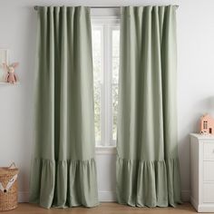 a green curtain with ruffles hanging in front of a white wall next to a window