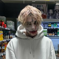 a man in a white hoodie with blood on his face and nose is standing in a store