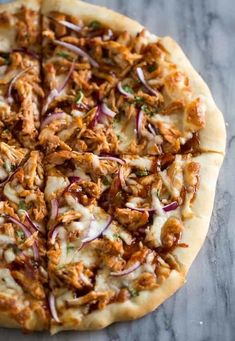 a pizza topped with meat and onions on top of a table