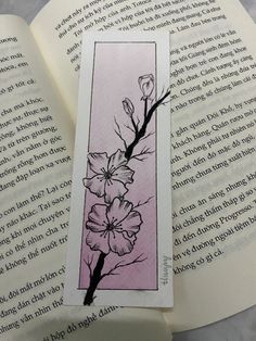 a bookmark with flowers on it sitting next to an open book