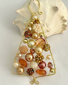 a christmas tree ornament made out of pearls and other beads on a white surface