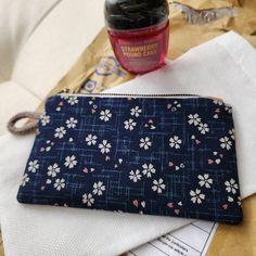 a blue flowered pouch sitting on top of a table next to a bottle of liquid