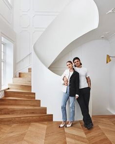 two people standing next to each other in front of a staircase