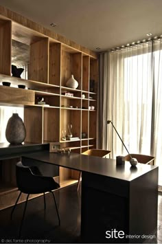 a home office with wooden shelves and black desk chair in front of the open bookcase