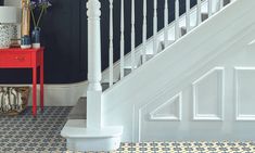 a red table sitting next to a white stair case in a room with black walls