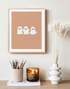 two ghost candles are sitting next to a candle holder on a table with some plants