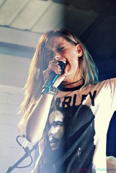 a woman singing into a microphone on stage