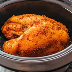 a close up of a chicken in a crock pot with seasoning on it