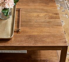 a wooden table topped with a vase filled with flowers and a pencil on top of it