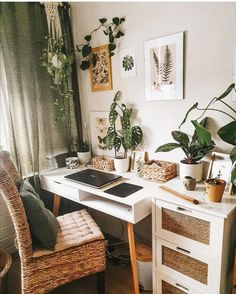 a home office with plants and pictures on the wall above it, along with wicker chairs