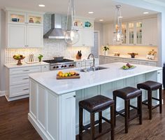 a large kitchen with an island in the middle and three stools next to it