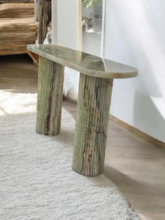 a wooden bench sitting on top of a white rug in a living room next to a doorway