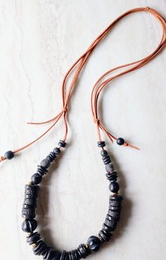 "Dark, organic, classic, everyday and everywhere. This necklace is 30\" in length. Soft beige-brown cord and array of black beads, disks, and spacers. This necklace is a staple wardrobe all year long. Would be beautiful on linen. Black African Recycled Glass beads in 12mm to 22mm in size.  Also a variety of wood beads, black disks, recycled glass beads, and fused glass. Full of interest and texture. Soft leather suede in natural beige-brown in this pull over head design. One-of-a-kind. The item/ Handmade Black Beaded Necklaces For Everyday, Artisan Black Adjustable Beaded Necklaces, Artisan Black Adjustable Beaded Necklace, Artisan Black Beaded Necklaces With Adjustable Fit, Adjustable Black Artisan Beaded Necklace, Adjustable Brown Necklace With Black Beads, Black Adjustable Necklace For Everyday Use, Adjustable Black Necklace For Everyday Use, Black Bohemian Necklace For Everyday Use