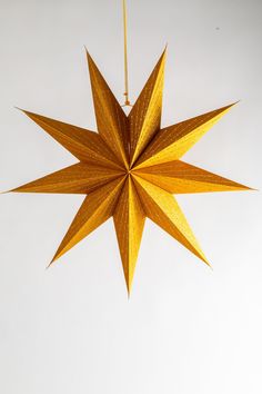 an origami star hanging from a string on a white wall with no background